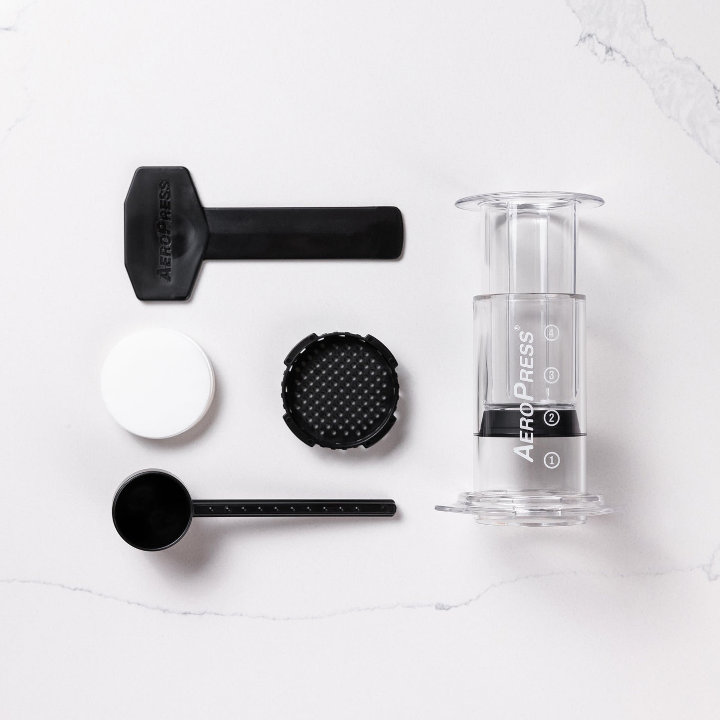 contenu de la boîte aeropress avec l'aeropress, le porte filtre, les filtres, la cueillère doseuse et le mélangeur