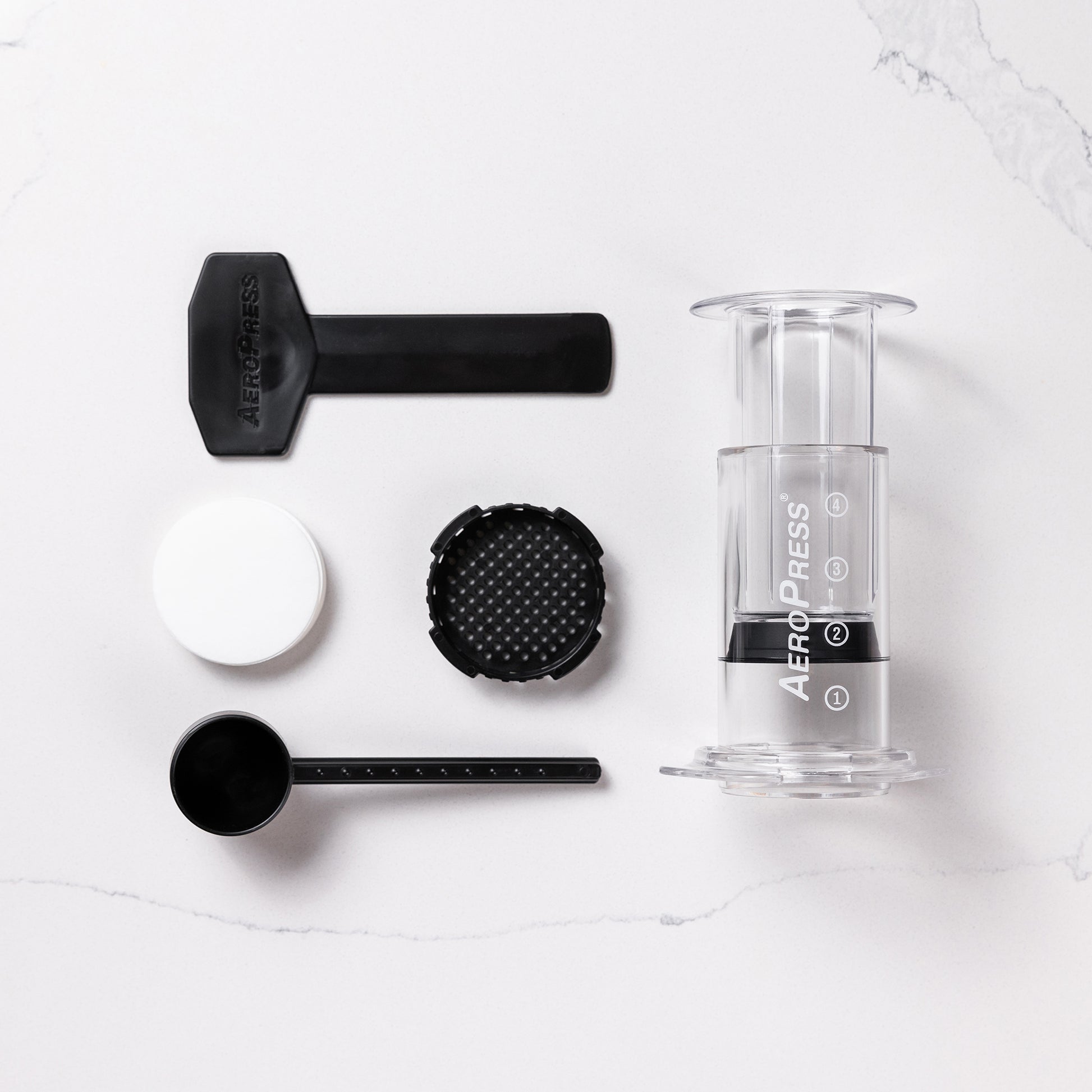 contenu de la boîte aeropress avec l'aeropress, le porte filtre, les filtres, la cueillère doseuse et le mélangeur
