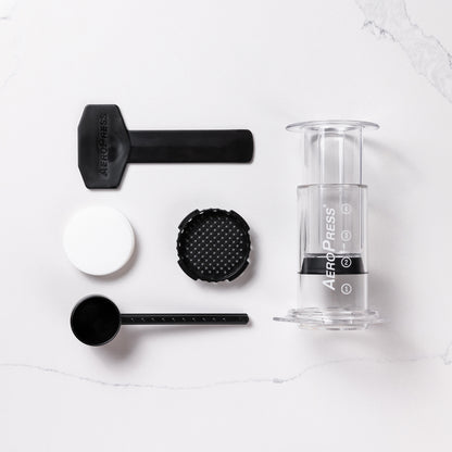 contenu de la boîte aeropress avec l'aeropress, le porte filtre, les filtres, la cueillère doseuse et le mélangeur