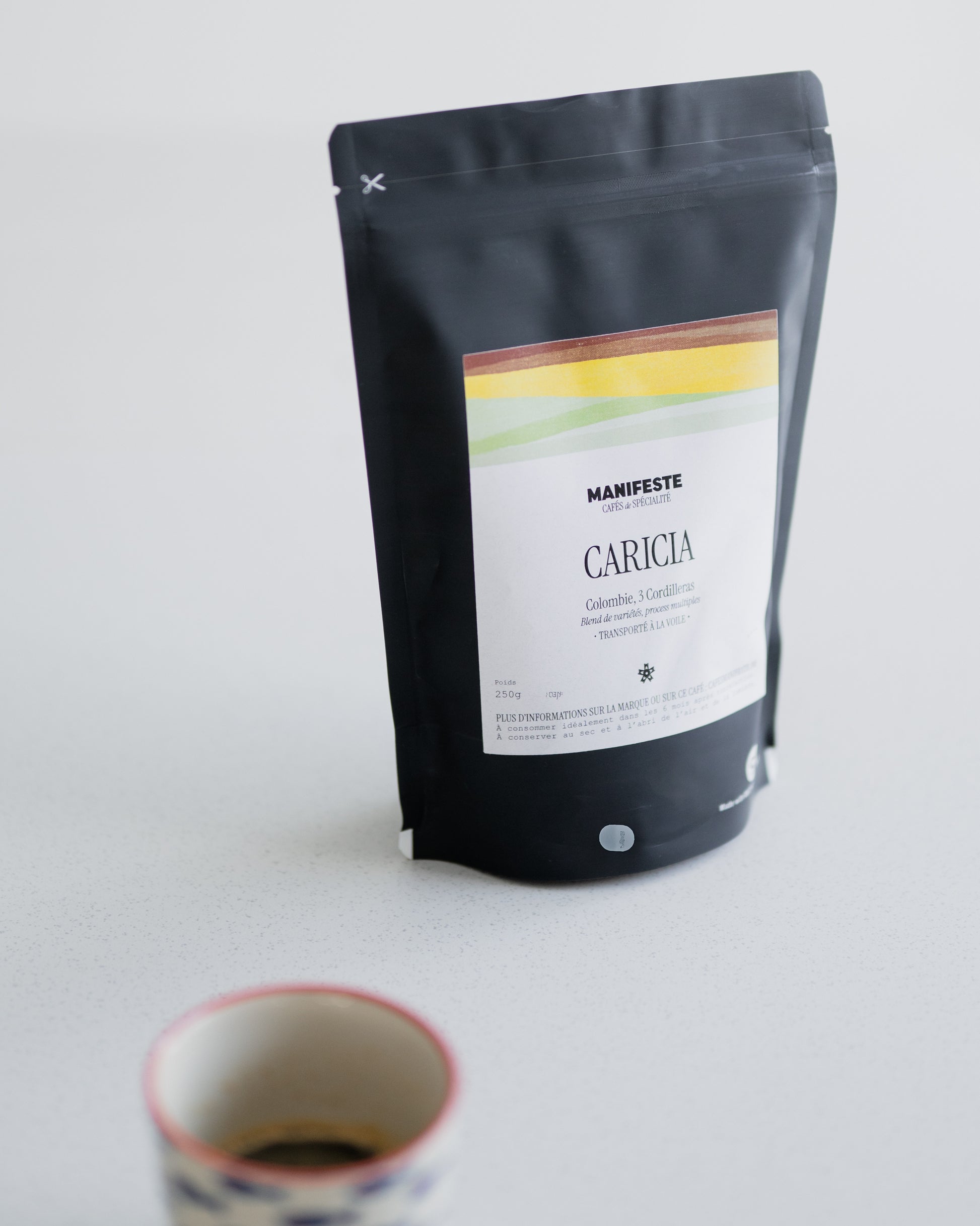 sachet de café espresso caricia vu de côté avec une tasse d'espresso au premier plan
